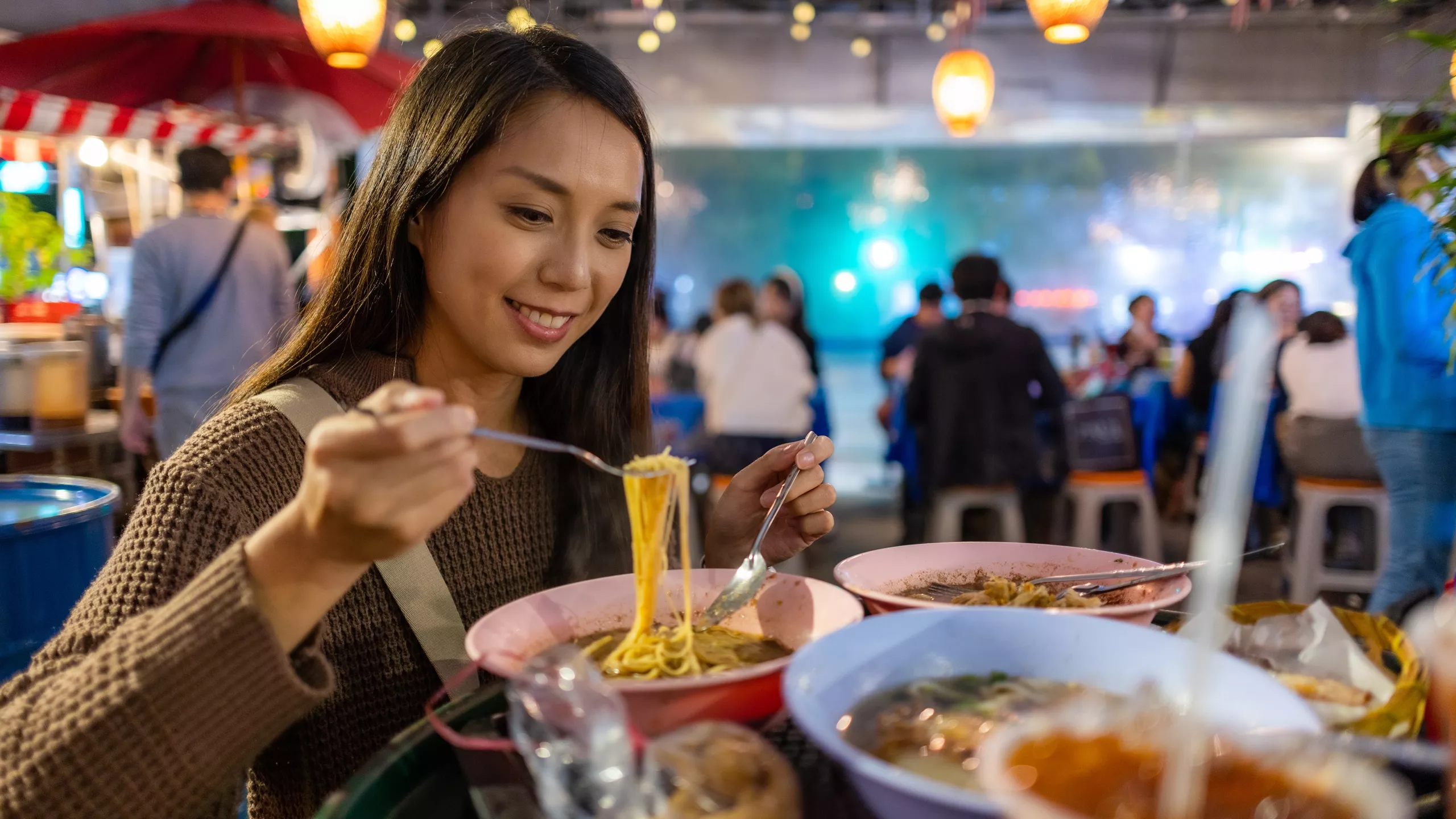 Eine junge asiatische Frau genießt ihre Nudeln in einem gemütlichen Asia Restaurant